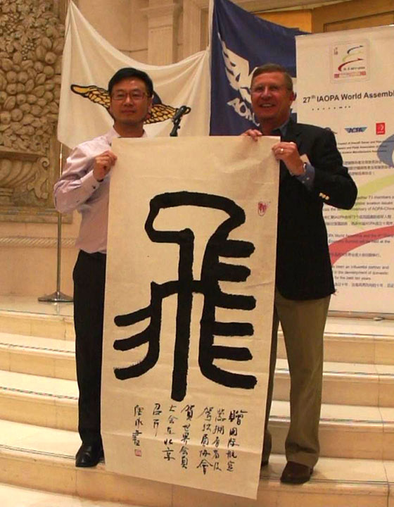 中国AOPA副秘书长唐永先生（左）即兴书写了一个篆体“飞”字，赠送给国际AOPA秘书长Craig Spence（右）